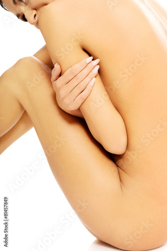 Nude woman sitting with knees close to chest