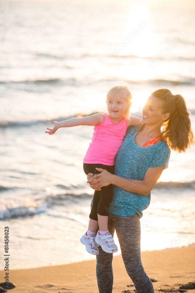 Healthy mother and baby girl pointing while on beach Healthy mother and baby girl pointing while on beach