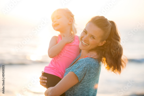 Portrait of healthy mother and baby girl on beach in the evening photo
