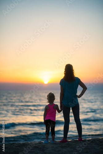 Silhouette of mother and baby girl on beach