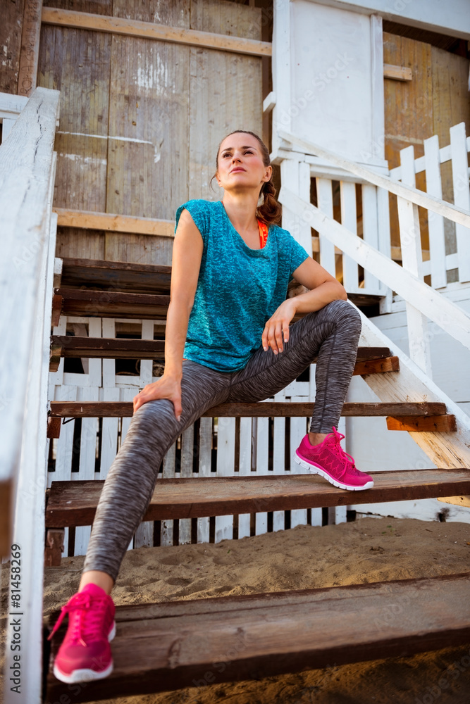 Fitness young woman sitting on stairs of beach house Fitness young woman sitting on stairs of beach house