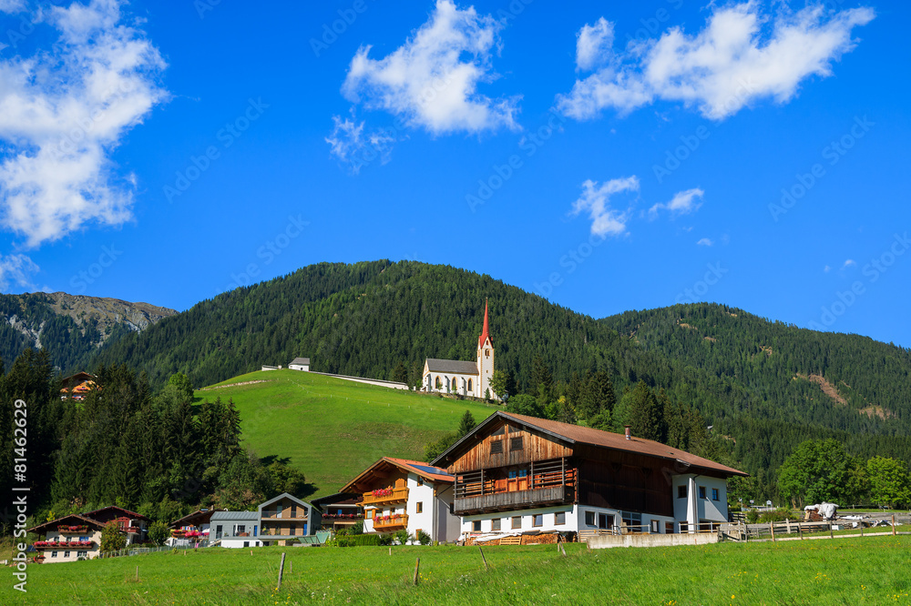 Green meadow and alpine houses in Strassen village, Austria