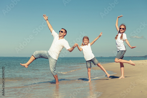 Father and daughters playing on the beach at the day time.