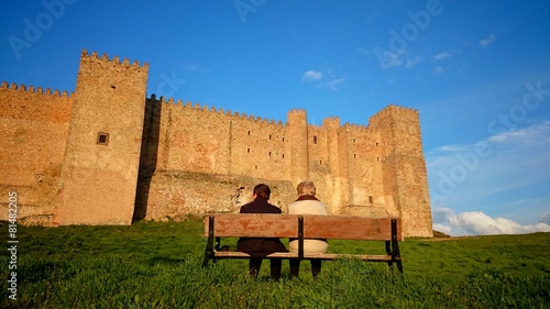 Abuelas sentadas en banco frente a castillo photo