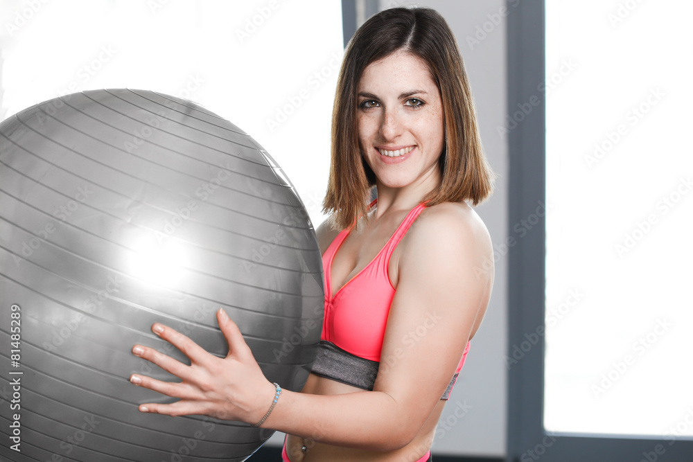 Fototapeta premium smiling woman with exercise ball in gym.