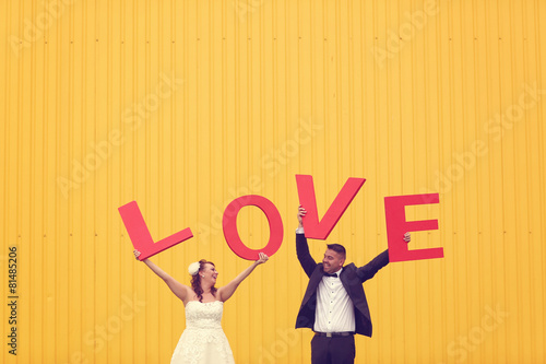 Bride and groom holding big love letters © hreniuca