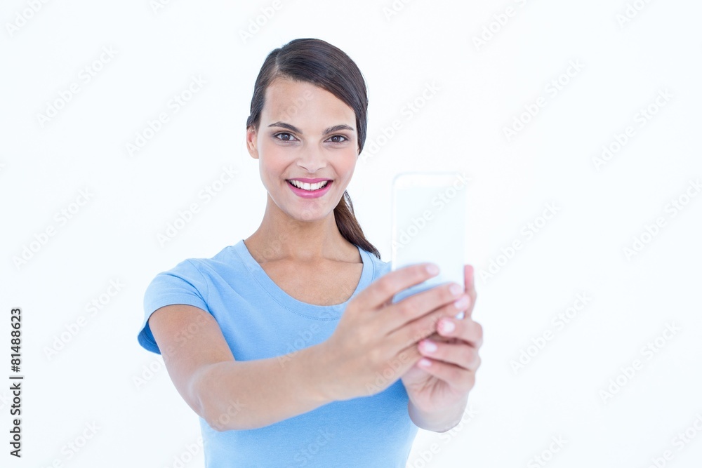Pretty brunette using her smartphone looking at camera Pretty brunette using her smartphone looking at camera