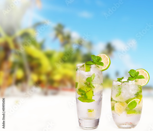 Mojito drink, Hat and flip-flops with tropical beach background,