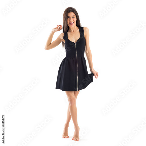 Smiling brunette woman with black dress barefoot isolated on whi