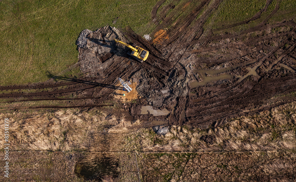 Obraz premium aerial view of long arm excavator working on the field