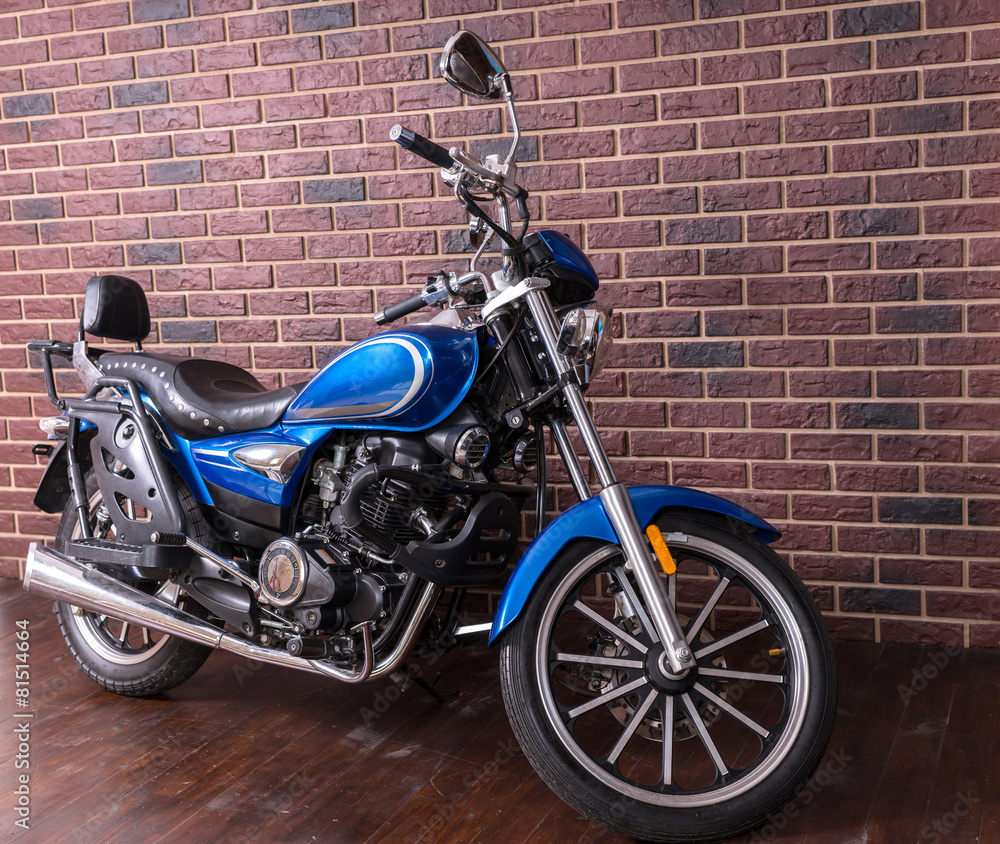 Blue motorbike parked in front of a brick wall