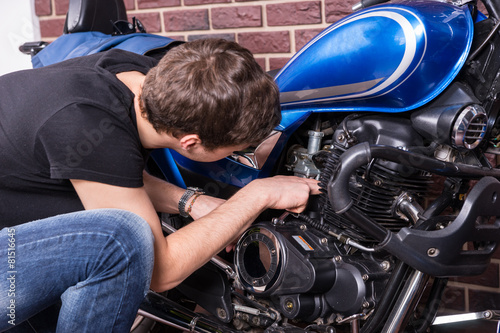 Obraz na płótnie Young Guy Fixing Some Parts of his Motorbike w salonie