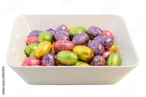 Many chocolate Easter eggs in colorful wrappings in a bowl