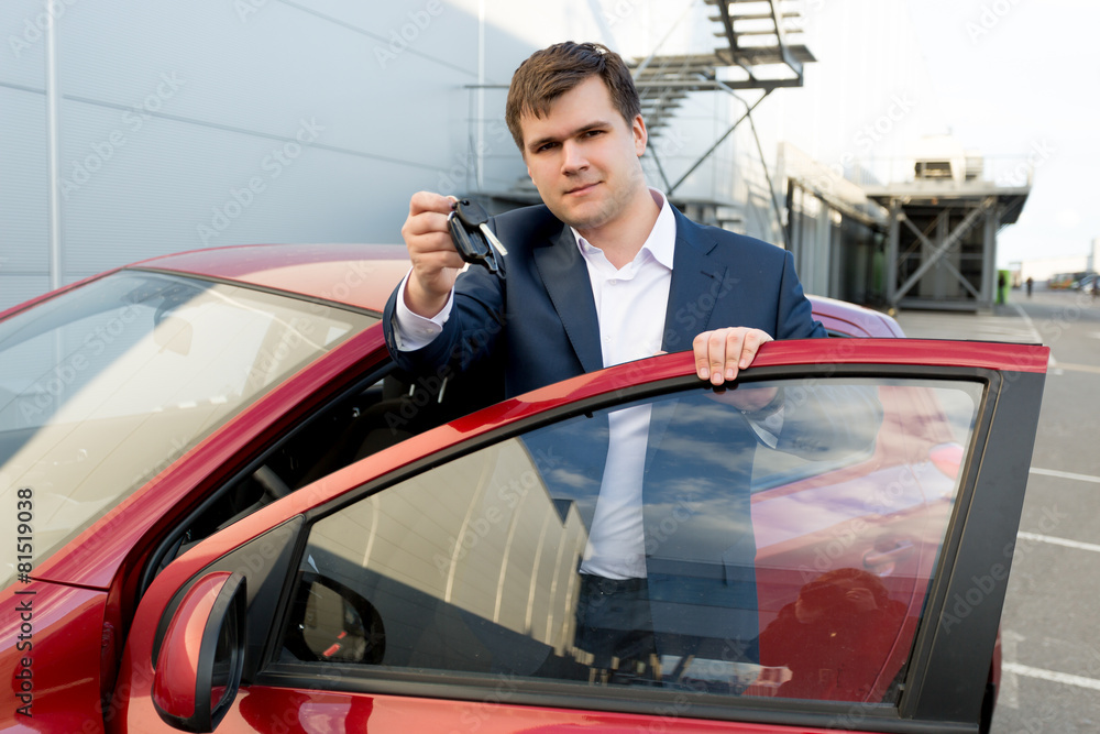 Portrait of happy businessman posing at car with keys Portrait of happy businessman posing at car with keys