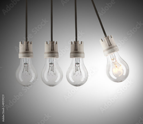 Fotografi Light bulbs in row with single one shinning