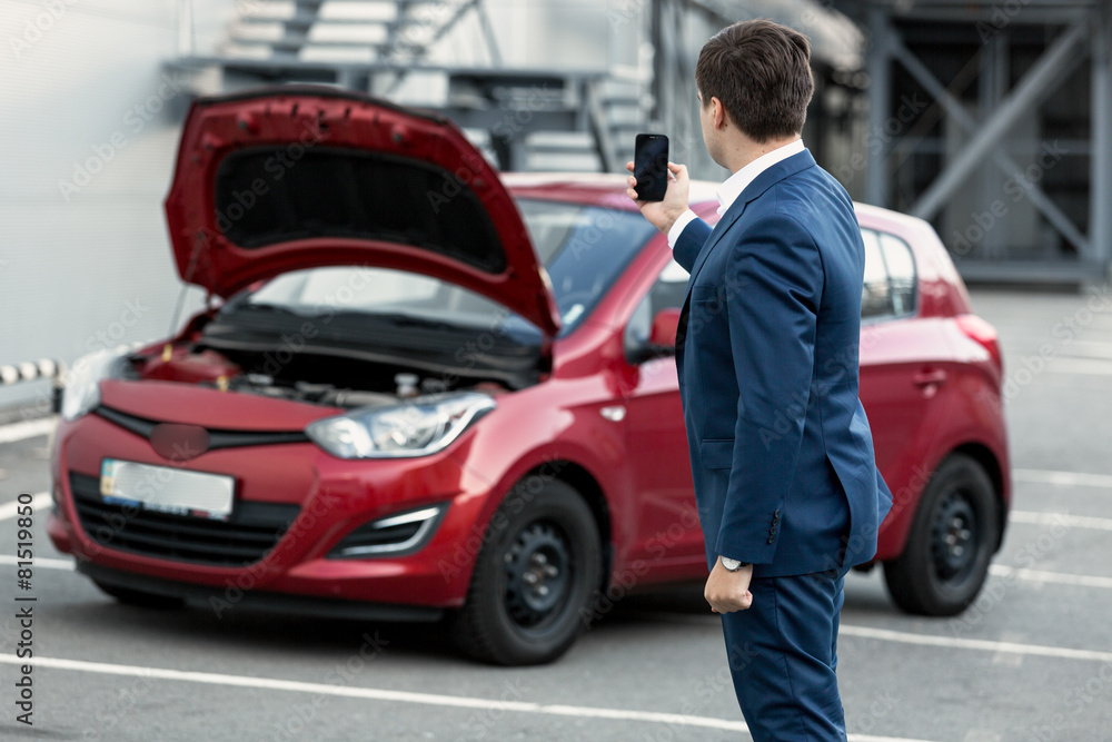 businessman making photo on phone of breakdown car for insurance