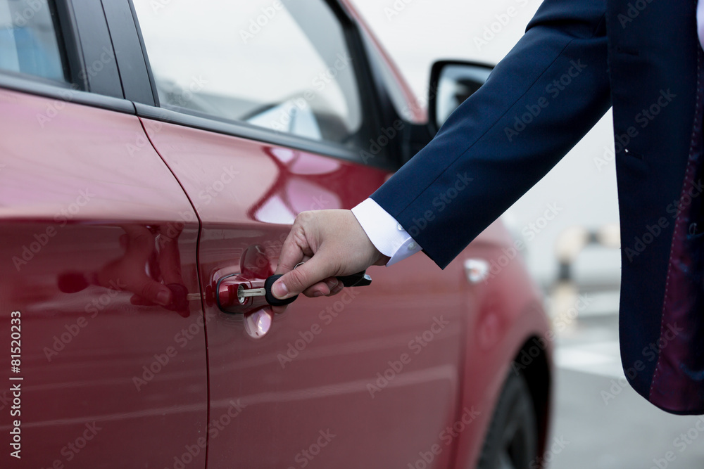 Closeup of businessman hand opening car door