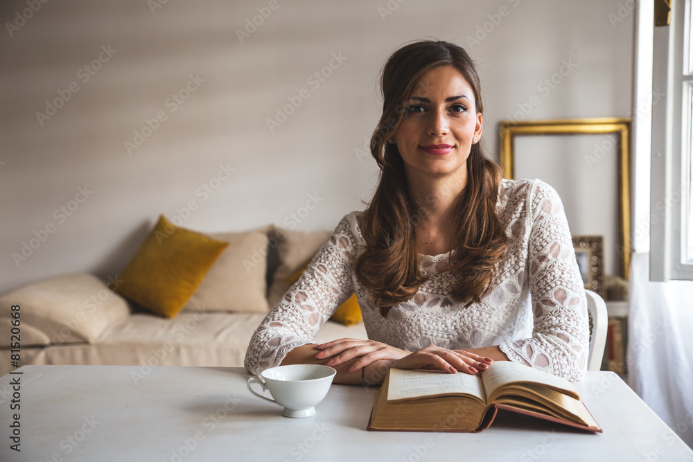 Charming woman sitting by wooden table and reading book Charming woman sitting by wooden table and reading book