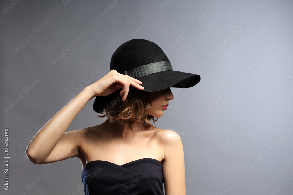 Portrait of beautiful model in black dress and hat on gray background Portrait of beautiful model in black dress and hat on gray background