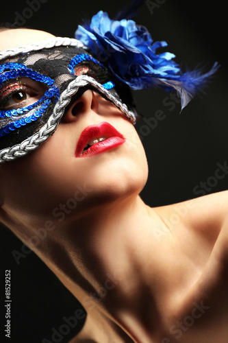 Portrait of beautiful woman with fancy glitter makeup and Masquerade mask on dark background
