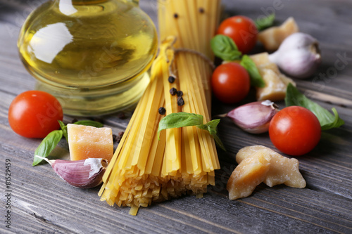 Raw pasta with cheese and vegetables on wooden background