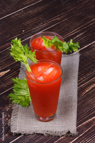 Bloody mary cocktails served with celery on wooden background