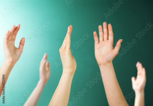 Raised hands on blackboard background in class