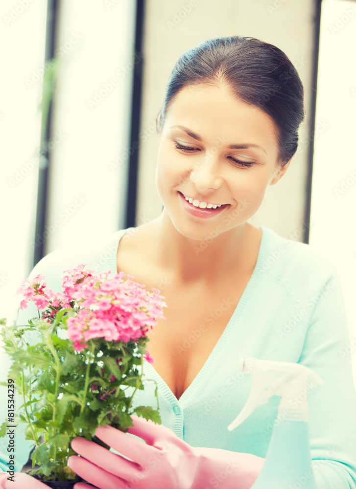 woman holding pot with flower and spray bottle woman holding pot with flower and spray bottle