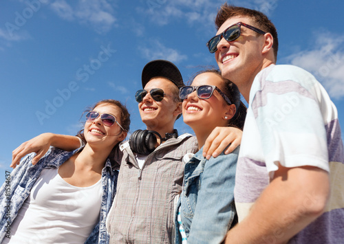 smiling teenagers in sunglasses hanging outside