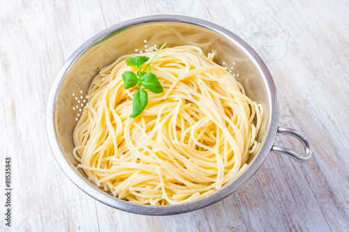 cooked pasta in the strainer on white wooden table
