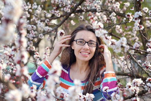 Brunette in glasses on a background of a blossoming tree in spri