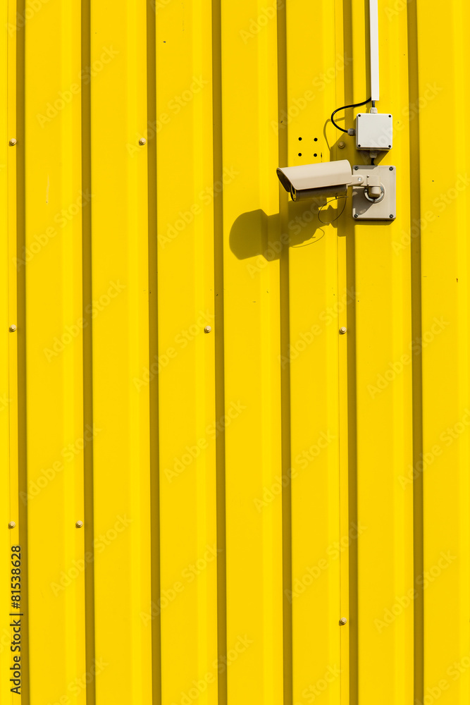 Security camera on a yellow wall