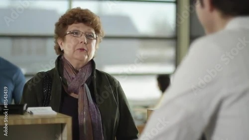 Happy female customer conducts business with bank teller.  
