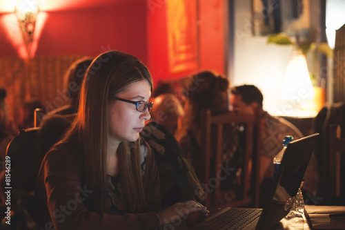 Student working on laptop in a public place such as a bar or pub