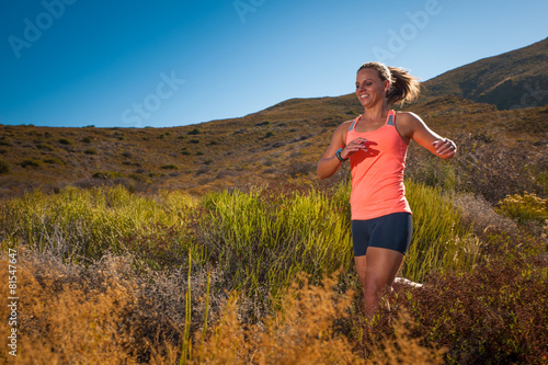 Blonde female trail runner running through a mountain landscape