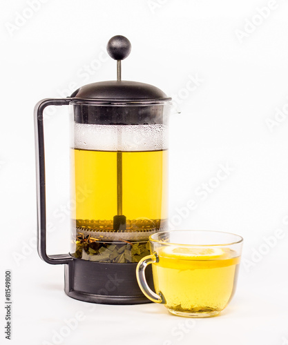 Transparent tea kettle and cup of tea with yellow tea