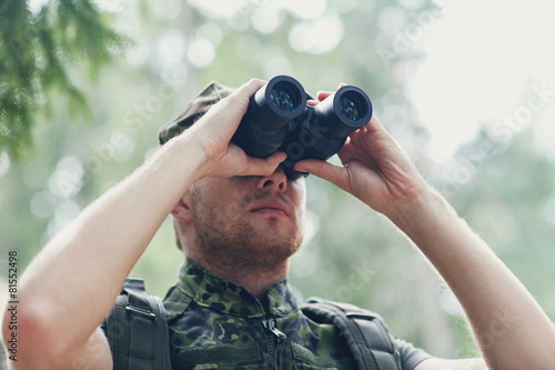 young soldier or hunter with binocular in forest