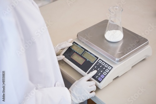 Fotografie Scientist weighing beaker with white powder inside