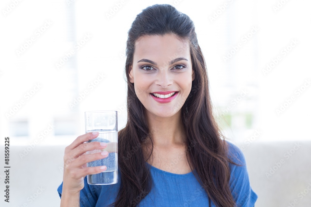 brunette sitting on the couch and holding glass of water brunette sitting on the couch and holding glass of water