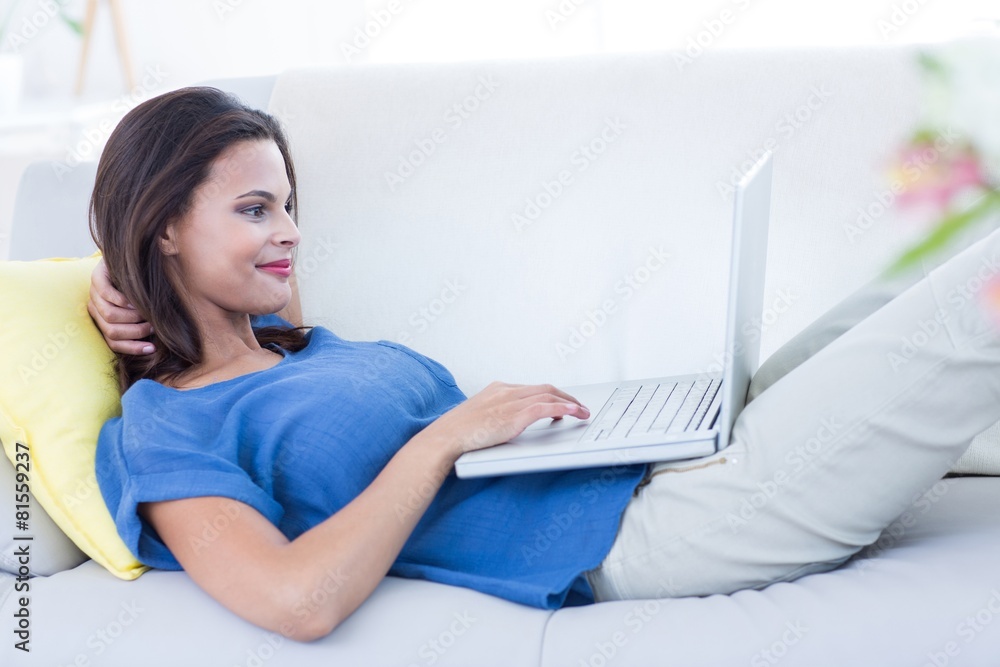 brunette relaxing on the couch and using her laptop brunette relaxing on the couch and using her laptop