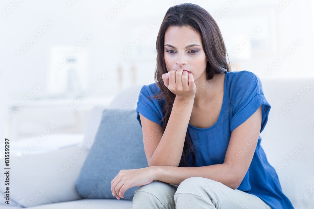 Thoughtful beautiful brunette sitting on the couch Thoughtful beautiful brunette sitting on the couch