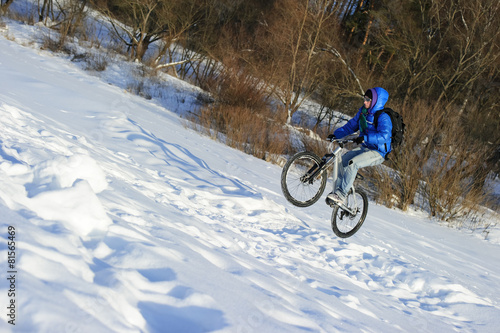 Bicyclist extreme jumping on mountain bike in snow winter field