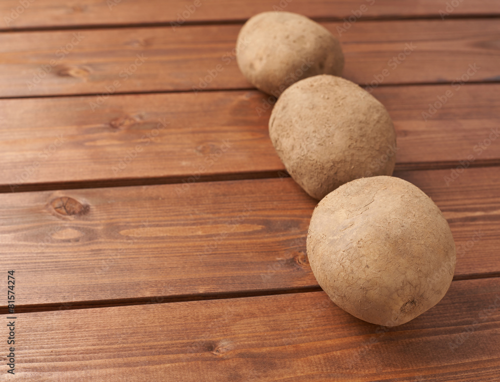 Three potatoes over the wooden surface Three potatoes over the wooden surface