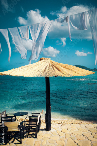 Row of Straw umbrellas and lounges at  beach photo