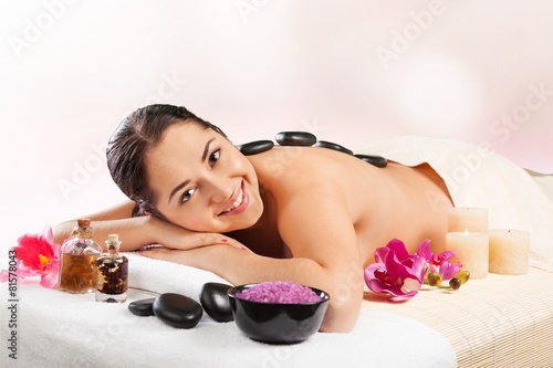 Adult. Adult woman relaxing in spa salon with hot stones on body photo