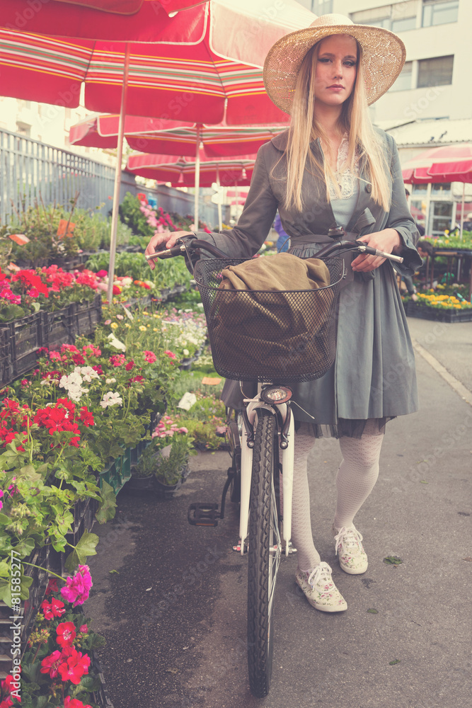 Attractive blonde girl with straw hat and bike on Marketplace.