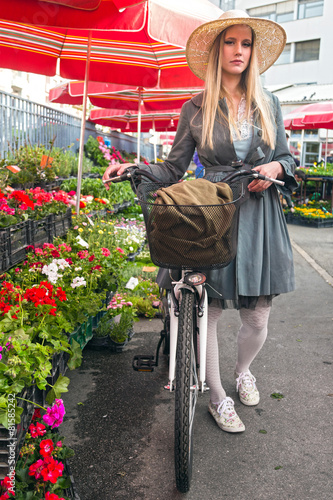 Attractive blonde girl with straw hat and bike at market. photo