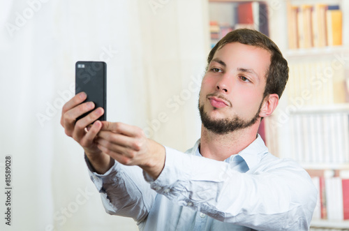 attractive young man using cell phone to take a selfie