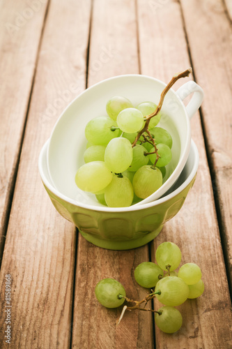 Fresh grapes in cup over wooden background with retro filter