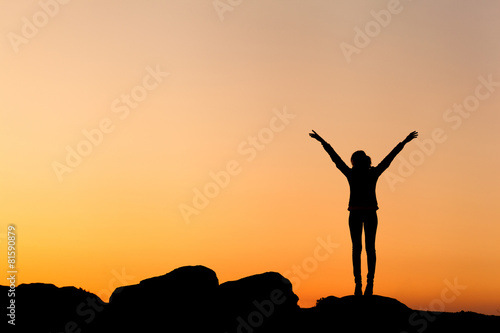 Silhouette of а happy young woman with arms raised up photo